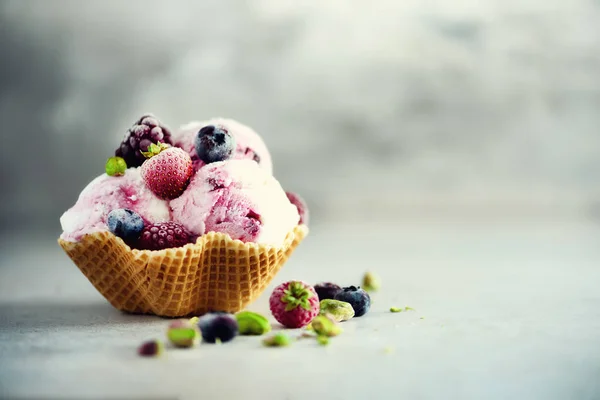 Pink ice cream with berries, strawberries, blueberries, raspberries, pistachios in waffle basket. Summer food concept, copy space. Healthy gluten free fruit ice-cream — Stock Photo, Image