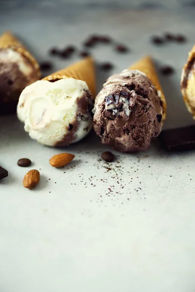 Chocolate and coffee ice cream in waffle cone with coffee beans on grey stone background. Summer food concept, copy space. Healthy gluten free ice-cream. Top view