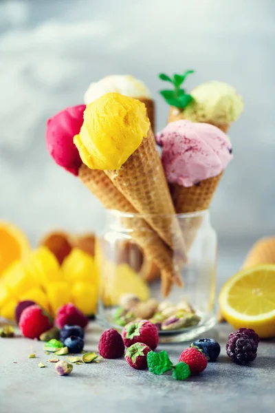 Colorful ice cream balls in waffle cones with different flavors - mango, lime, mint, pistachio, orange, strawberries, raspberries, blueberries. Summer concept — Stock Photo, Image