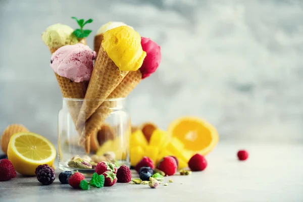 Colorful ice cream balls in waffle cones with different flavors - mango, lime, mint, pistachio, orange, strawberries, raspberries, blueberries. Summer concept — Stock Photo, Image