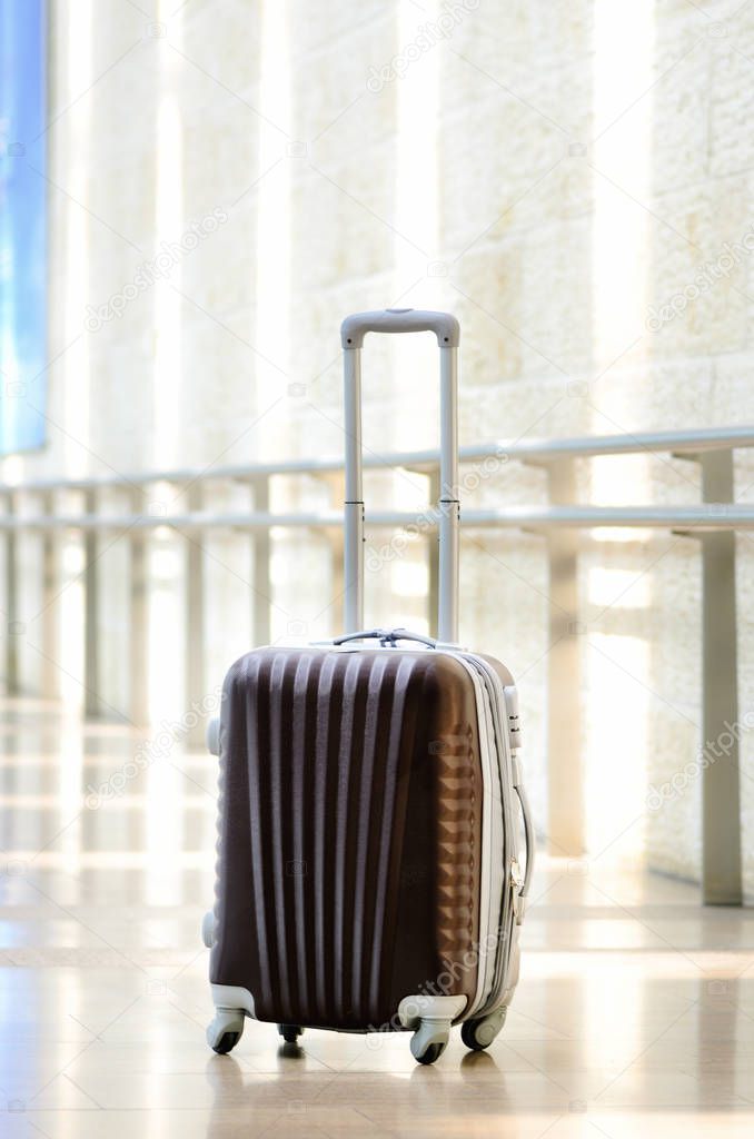 Packed travel suitcase, airport. Summer holiday and vacation concept. Traveler baggage, brown luggage in empty hall interior. Copy space
