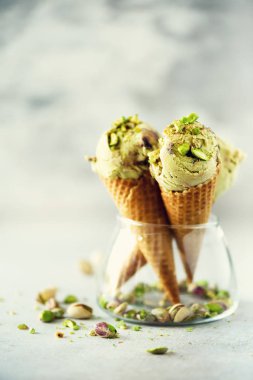 Yeşil dondurma waffle koni gri taş zemin üzerine çikolata ve fıstık fındık ile. Yaz gıda kavramı, kopya alanı. Sağlıklı gluten ücretsiz dondurma. Afiş