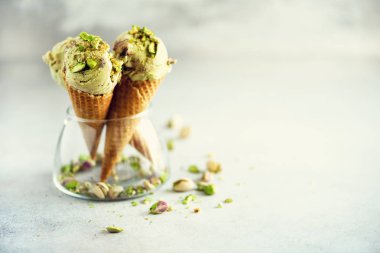 Yeşil dondurma waffle koni gri taş zemin üzerine çikolata ve fıstık fındık ile. Yaz gıda kavramı, kopya alanı. Sağlıklı gluten ücretsiz dondurma. Afiş