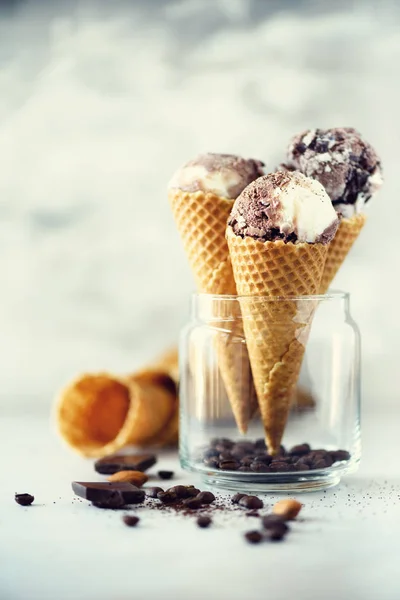 Chocolate and coffee ice cream in waffle cone with coffee beans on grey stone background. Summer food concept, copy space. Healthy gluten free ice-cream. Banner