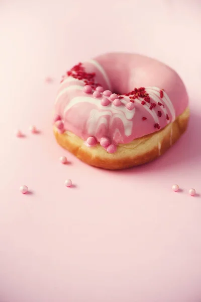 Сладкий пончик с розовой глазурью на фоне пастели. Вкусный пончик на розовой текстуре, пространство для копирования, вид сверху — стоковое фото