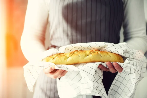 Руки женщины держат свежеиспеченный хлеб. Французский багет, концепция пекарни, домашняя еда, здоровое питание. Копирование пространства — стоковое фото