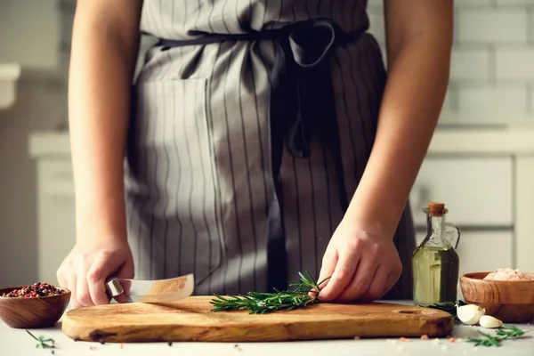 Manos de mujer cortando romero verde fresco sobre tabla de cortar de madera en la cocina blanca, interior. Copiar espacio. Comida casera engreída, receta saludable. Llévame a trabajar. — Foto de Stock