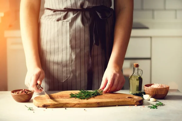 Manos de mujer cortando romero verde fresco sobre tabla de cortar de madera en la cocina blanca, interior. Copiar espacio. Comida casera engreída, receta saludable. Llévame a trabajar. —  Fotos de Stock