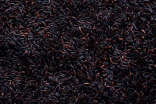 Rosso scuro crudo, riso viola balck, consistenza. sfondo modello di riceberry. Sfondo ingrediente alimentare. Vista dall'alto, concetto di stile di vita sano . — Foto Stock