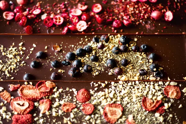 Handmade chocolate bars with dried cranberries, raspberries and pistachios, strawberries, nuts. Dark and milk chocolate mix, assortment. Top view