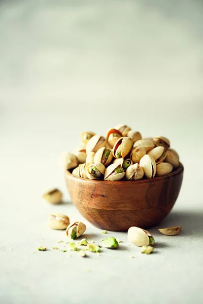 Green salted pistachios in wooden bowls on light concrete background. Copy space for your text. Healthy nuts snack. Banner — Stock Photo, Image