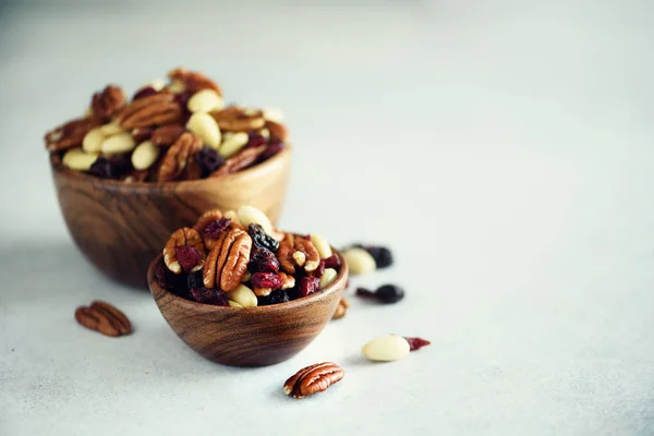 Nueces y pasas mezcladas en un tazón de madera. Comida y merienda saludables. Nuez, pistachos, almendras, avellanas, anacardos, pasas. Banner — Foto de Stock