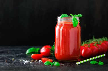 Bir cam kavanoz, fesleğen, kiraz, tuz, biber ve saman koyu siyah arka plan üzerine organik taze domates suyu. Yemek temizlik ve kavram diyet. Kopya alanı