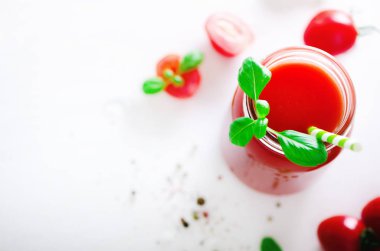 Bir cam kavanoz, fesleğen, kiraz, tuz, biber ve saman ışık arka plan üzerinde organik taze domates suyu. Yemek temizlik ve kavram diyet. Kopya alanı.