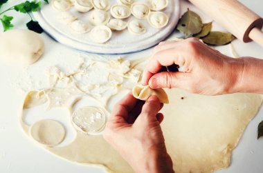 Geleneksel Rus mantı, mantı, mantı beyaz beton zemin üzerine etli. Maydanoz, bıldırcın yumurtası, biber, biberiye, defne yaprağı ve baharat. Üstten Görünüm. Kopya alanı
