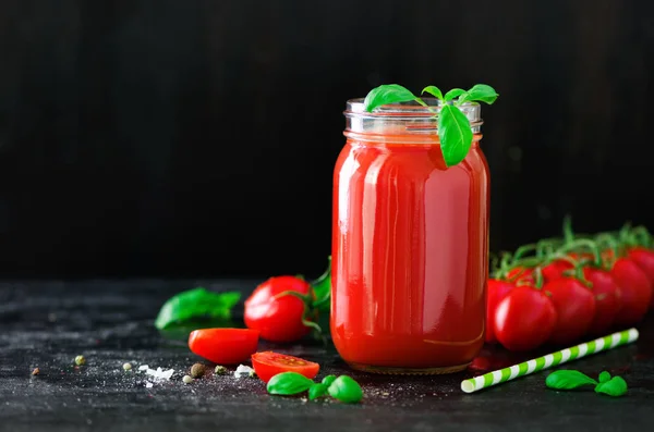 Органический свежий томатный сок в стеклянной банке, базилике, вишне, соли, перце и соломе на темном черном фоне. Концепция чистого питания и диеты. Копирование пространства — стоковое фото