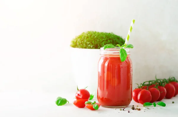 Biologische verse tomatensap in een glazen pot, basilicum, kers, zout, peper en stro op een lichte achtergrond. Schoon eten en dieet concept. Kopieer ruimte. Banner — Stockfoto