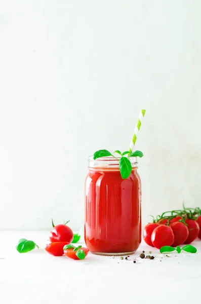 Organic fresh tomato juice in a glass jar, basil, cherry, salt, pepper and straw on light background. Clean eating and diet concept. Copy space. — Stock Photo, Image