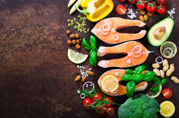 Filete de salmón sin cocer con hierbas aromáticas, cebolla, aguacate, brócoli, pimiento, verduras sobre fondo de madera, vista superior. Ingredientes para cocinar sobre fondo . — Foto de Stock