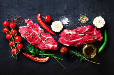 Çiğ taze et biftek domates, acı biber, sarımsak, yağ ve otlar karanlık taş, beton arka plan ile. Metniniz için boş alan