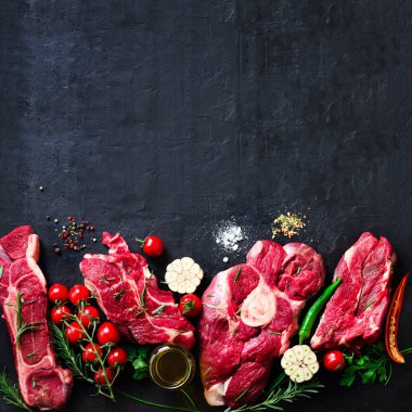 Çiğ taze et biftek domates, acı biber, sarımsak, yağ ve otlar karanlık taş, beton arka plan ile. Metniniz için boş alan