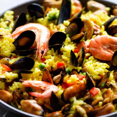 Geleneksel İspanyol deniz ürünleri paella pan pirinç, bezelye, karides, midye, mürekkep balığı ışık üzerinde beton arka plan gri. Üstten Görünüm boşaltmak. Kare kırpma