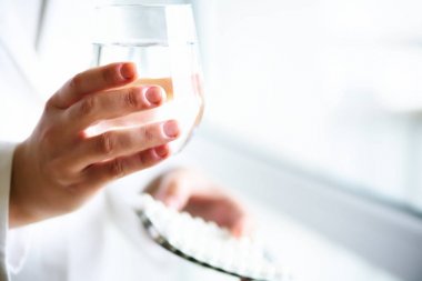 Bir bardak su ile uyuşturucu, ilaç, beyaz arka plan tutan doktor. Uzay kopyalayın. Tıp kavramı.