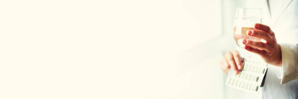 Doctor holding a glass of water with drug, pills, white background. Copy space. Banner. Medicine concept.