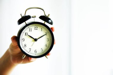 Klasik siyah çalar saat içinde bir el. Güneşli sabah ışık. Kopya alanı.