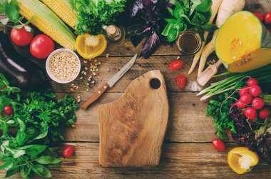 Ahşap arka plan üzerinde sebze. Otlar, fesleğen, soğan, kabak, çam fıstığı, domates, Mısır, turp, patlıcan, biber, tuz, baharat, yağı, ıspanak, maydanoz, marul yaprakları. Üstten Görünüm, kopya alanı