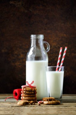 Noel koyu arka plan kar ve bokeh, kopya alanı ile. Şişe, Santa, tanımlama bilgileri, kırmızı ip, anason yıldız, tarçın, koniler, dekor ahşap antika tablo için süt ile cam.