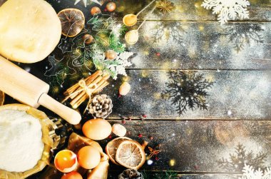 Noel arka plan - koniler, çam ağacı, hamur, un, oklava, yumurta, yumurta yolksover, baharat, Kuru portakal, eski koyu ahşap arka plan. Üstten Görünüm, kopya alanı, kar, bokeh.