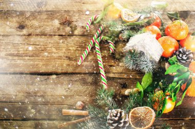 Sihirli Noel arka plan - vintage ahşap, şeker kamışı, house, tarçın, yıldız anason, yeşil yaprakları, koniler, kar taneleri ile tatlı mandalina. Yeni yıl. Üstten Görünüm, kopya alanı, kar, bokeh.