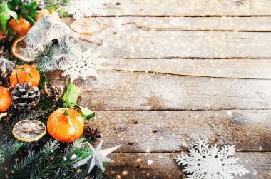 Sihirli Noel arka plan - vintage ahşap, şeker kamışı, house, tarçın, yıldız anason, yeşil yaprakları, koniler, kar taneleri ile tatlı mandalina. Yeni yıl. Üstten Görünüm, kopya alanı, kar, bokeh.