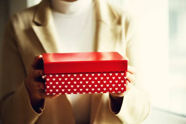 Les mains féminines tenant boîte cadeau rouge avec des cœurs blancs, espace de copie. Noël, année de coupe, anniversaire, concept de Saint Valentin. Bannière — Photo