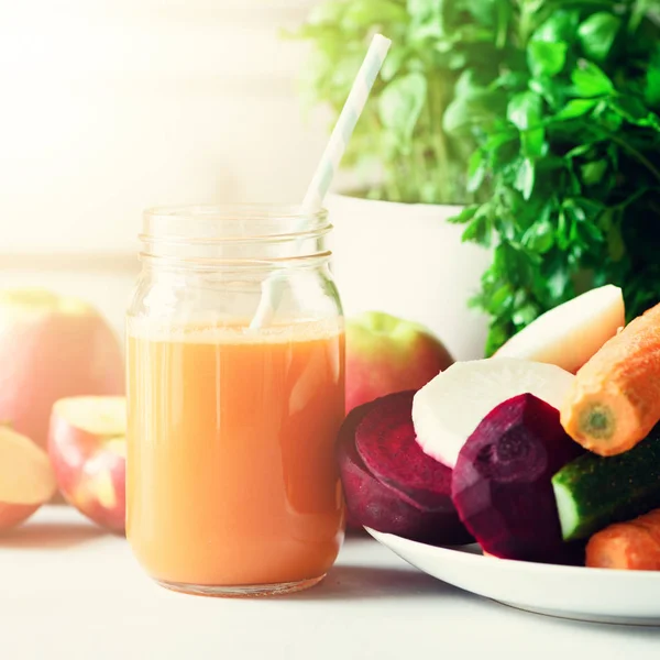 Une femme qui prépare des boissons fraîches. Jus de fruits et jus de carotte. Fruits en arrière-plan. Manger propre, concept de désintoxication — Photo