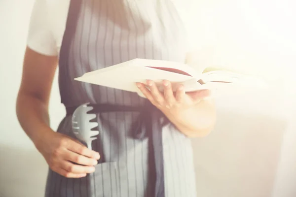 Menina vestindo avental cinza e livro de leitura. Conceito de estilo de vida — Fotografia de Stock