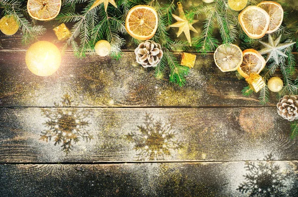 Tarjeta de felicitación navideña con regalos, velas, conos, palitos de canela, naranja seca, árbol verde sobre fondo de madera oscura vieja. Vista superior con espacio de copia para el texto. Nieve y bokeh — Foto de Stock