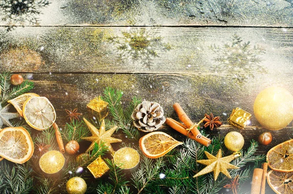 Рождественская открытка с подарками, свечами, конусами, коричными палочками, сухим апельсином, зеленым деревом на старом темном фоне дерева. Вид сверху с пространством для копирования текста. Снег и боке — стоковое фото