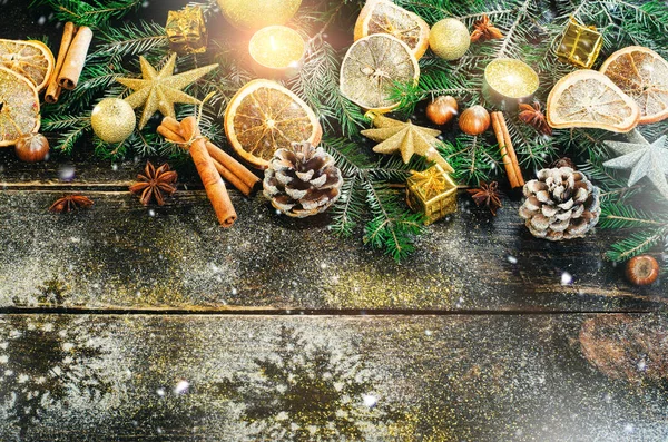 Tarjeta de felicitación navideña con regalos, velas, conos, palitos de canela, naranja seca, árbol verde sobre fondo de madera oscura vieja. Vista superior con espacio de copia para el texto. Nieve y bokeh — Foto de Stock