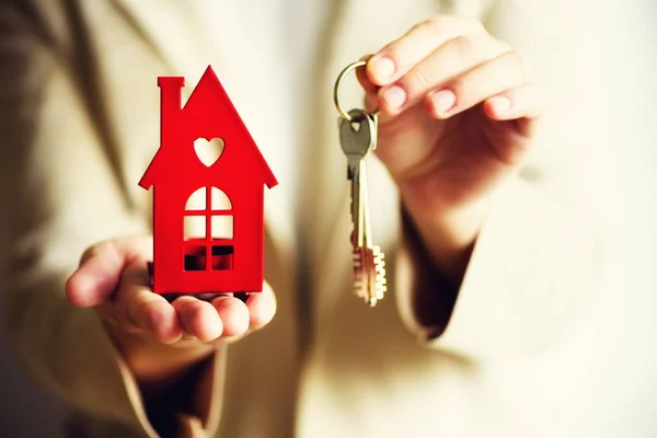 Female hands holding small red house and keys. Real estate agent offer you house or apartment. Property insurance and security concept. Copy space Stock Photo