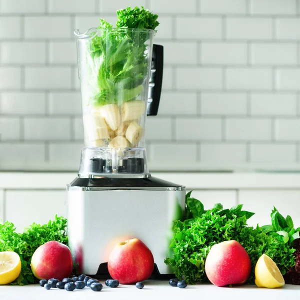 Vrouw mengen sla bladeren, spinazie, aplles, bessen, bananen. Zelfgemaakte gezonde groene smoothie. Witte keukenontwerp. Plein — Stockfoto