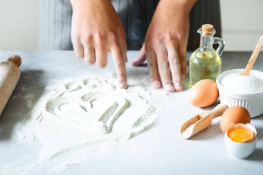 Un kalbinde. Arka plan ile oklava, yumurta, süt pişirme, beyaz mutfak masasında tereyağı. Yemek, Sevgiliye aşk kavramı.