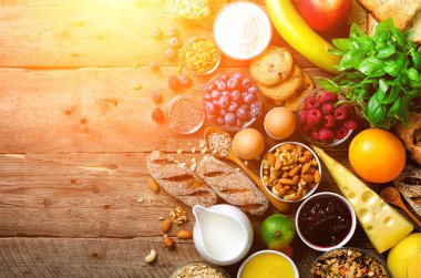 Sağlıklı kahvaltı maddeler, gıda çerçeve. Granola, yumurta, fındık, meyve, çilek, kızarmış ekmek, süt, yoğurt, portakal suyu, peynir, muz, elma ahşap rustik arka plan, üstten görünüm, kopya alanı
