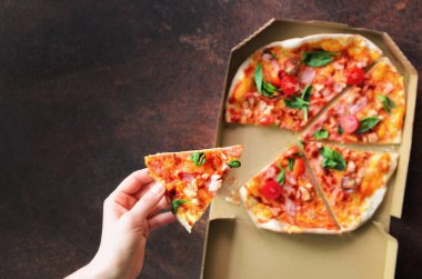 El alarak teslim kutusundan taze pizza yiyelim. Üstten Görünüm, koyu arka plan. Abur cubur
