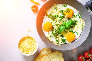 Güneşli sabah. Pan, otlar, baharatlar, kiraz domates, peynir tost, fesleğen gri Beton taş zemin üzerine kızarmış yumurtalı kahvaltı. Kopyalama alanı, üstten görünüm, düz lay, sunlights