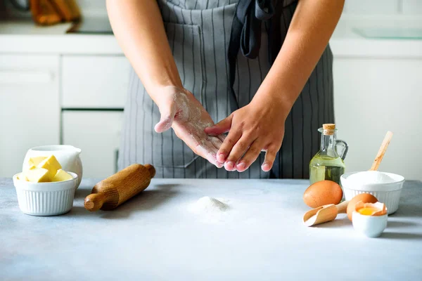 Mains féminines pétrissant la pâte, fond de cuisson. Ingrédients de cuisson œufs, farine, sucre, beurre, lait, rouleau à pâtisserie sur la cuisine de style blanc. Espace de copie — Photo