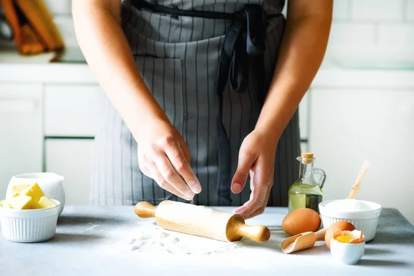 Manos femeninas amasando masa, horneando fondo. Cocinar los ingredientes - huevos, harina, azúcar, mantequilla, leche, rodillo en la cocina de estilo blanco. Copiar espacio — Foto de Stock