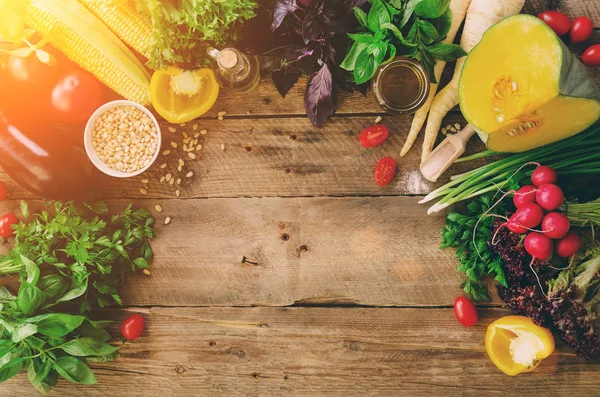 Vegetables on wooden background. Herbs, basil, onion, pumpkin, pine nuts, tomatoes, corn, radish, eggplant, bell pepper, salt, spices, oil, spinach, parsley, lettuce leaves. Top view, copy space — Stock Photo, Image