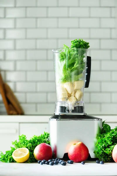 Mujer que mezcla hojas de lechuga, espinacas, aplausos, bayas, plátanos. batido verde sano casero. Diseño de cocina blanca — Foto de Stock